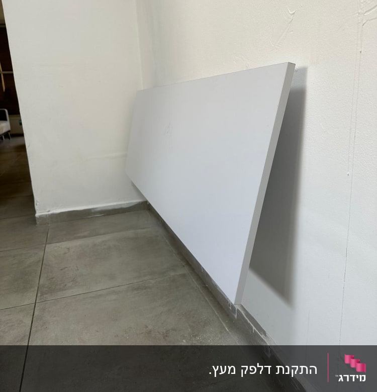 לוח עץ לבן מונח על קיר לבן